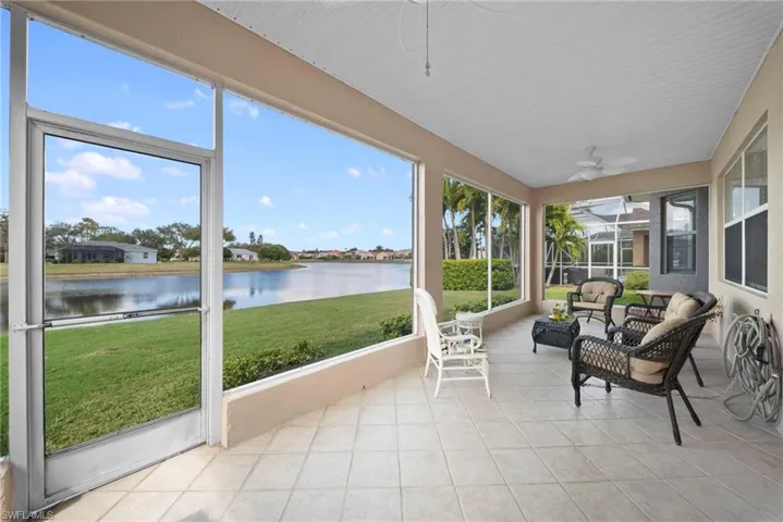 Sunroom / solarium featuring a ceiling fan and a water view