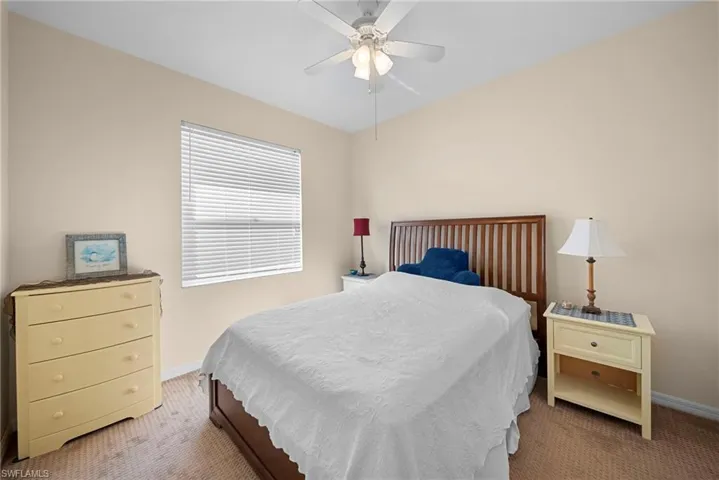 Carpeted bedroom with a ceiling fan and baseboards