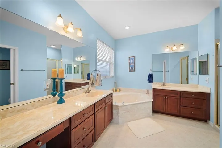 Bathroom with two vanities, a stall shower, a bath, and light tile patterned floors