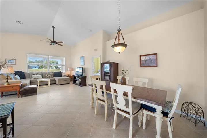 Dining area with vaulted ceiling, ceiling fan, and light tile patterned floors