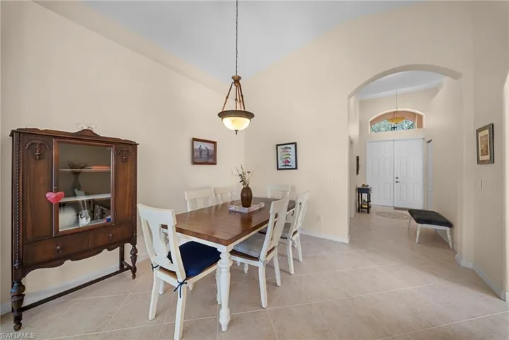 Dining space featuring arched walkways, vaulted ceiling, and light tile patterned floors