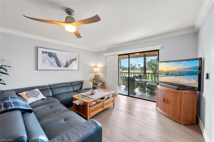 Living room with ceiling fan, ornamental molding, and light hardwood / wood-style floors