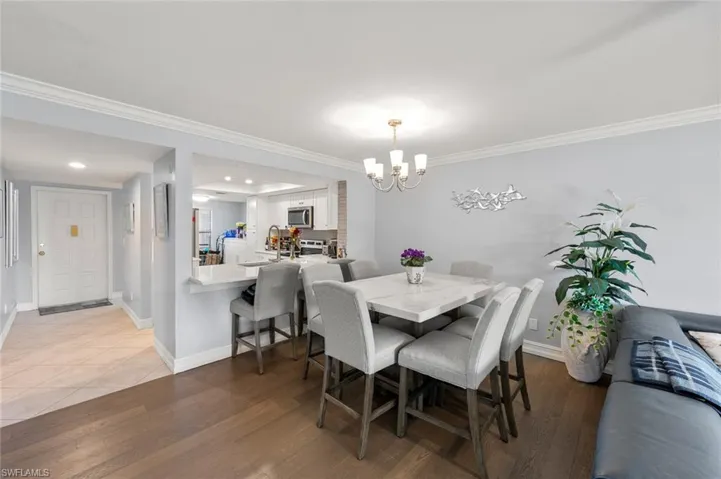 Dining room with sink, hardwood / wood-style flooring, crown molding, and a chandelier