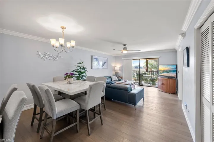 Dining room with hardwood / wood-style flooring, ornamental molding, and ceiling fan with notable chandelier