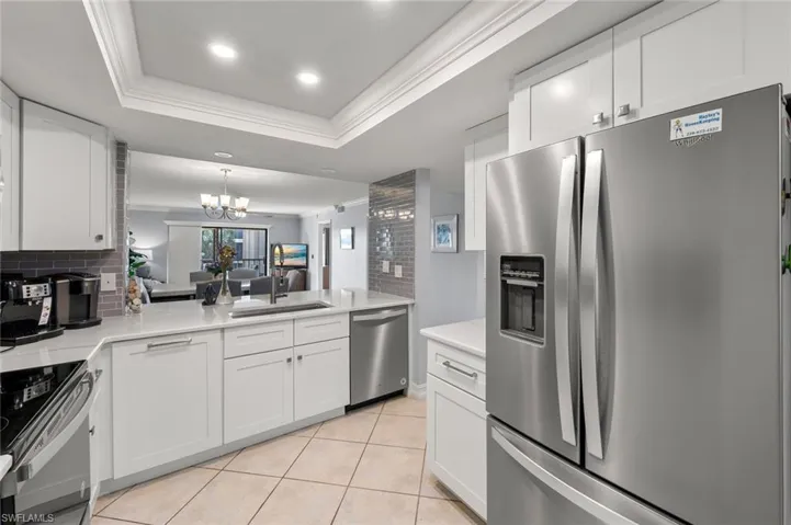 Kitchen with sink, stainless steel appliances, a raised ceiling, and white cabinets