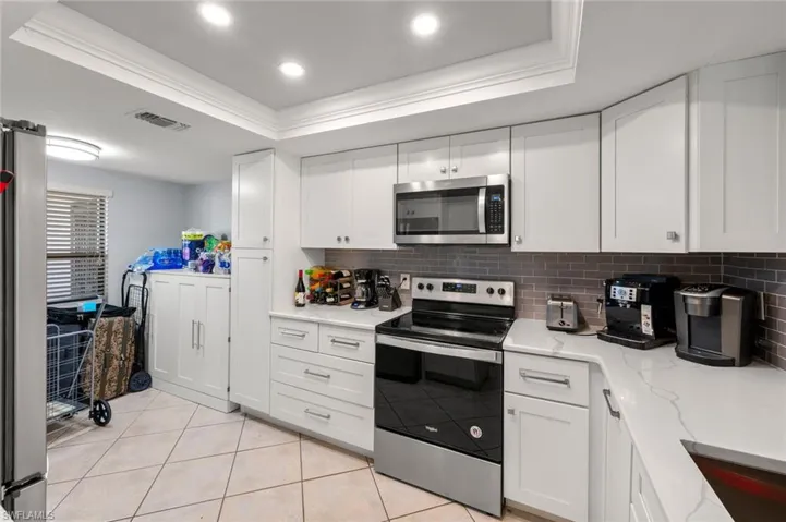 Kitchen with a tray ceiling, appliances with stainless steel finishes, and white cabinets