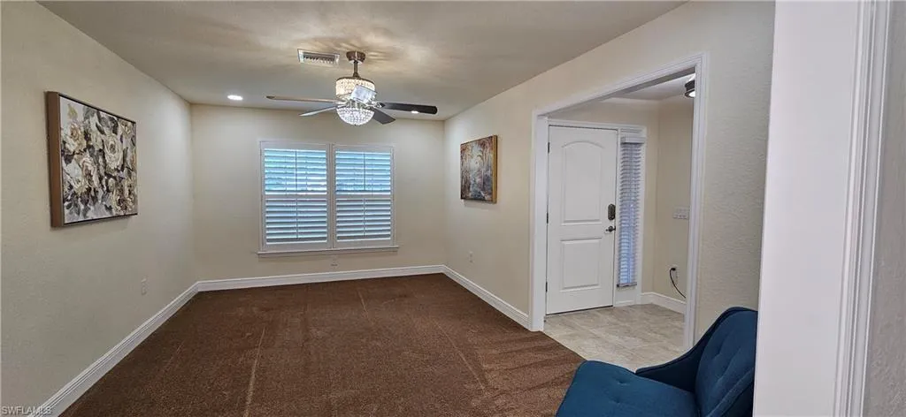 Unfurnished room with ceiling fan, baseboards, and carpet flooring
