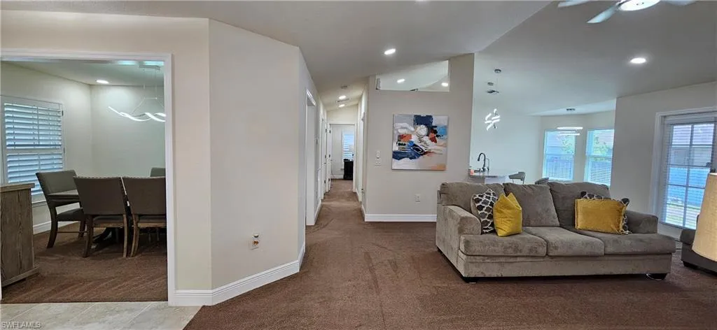Living room with carpet flooring, baseboards, vaulted ceiling, ceiling fan, and recessed lighting