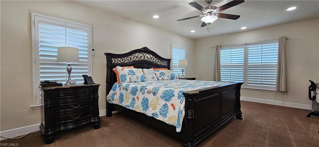 Bedroom with dark colored carpet, baseboards, recessed lighting, and a ceiling fan