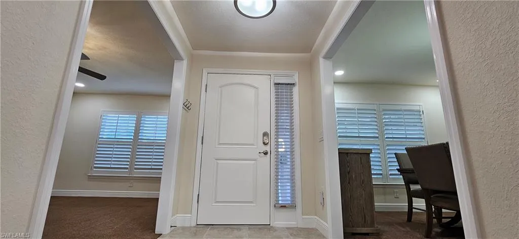 Foyer featuring a textured wall and baseboards