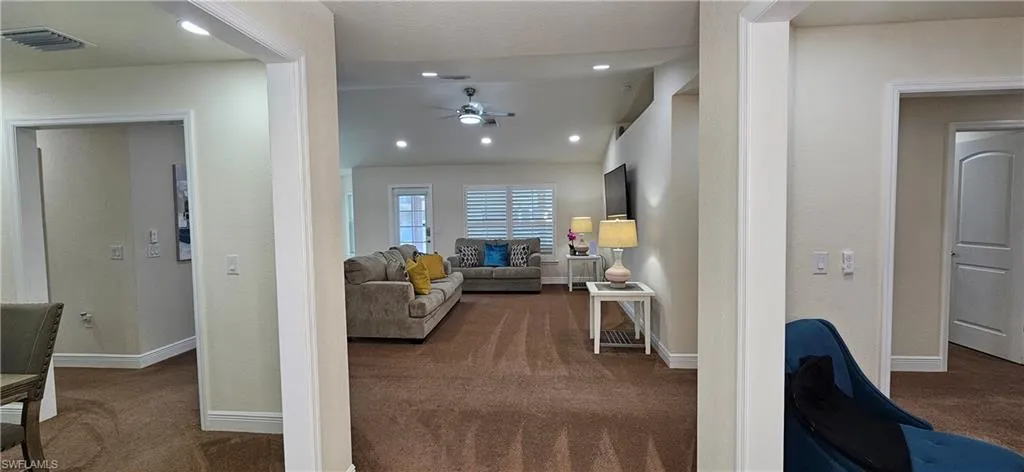 Carpeted living room with a ceiling fan, baseboards, and recessed lighting