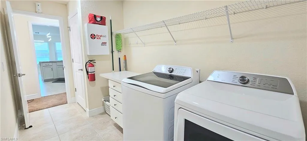 Laundry room featuring independent washer and dryer, baseboards, and light tile patterned floors