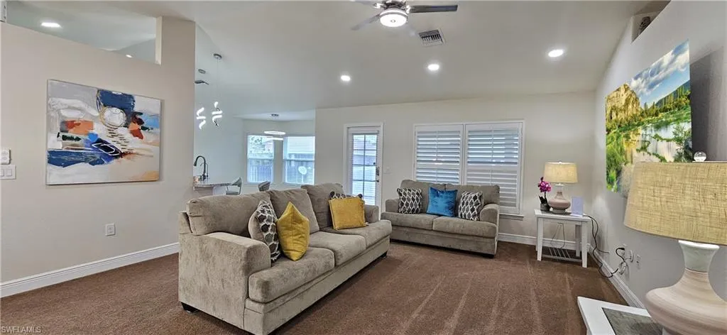 Carpeted living area with ceiling fan, baseboards, and recessed lighting