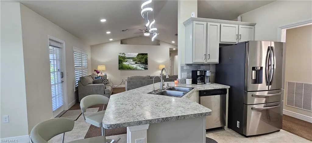 Kitchen with stainless steel appliances, a sink, open floor plan, vaulted ceiling, and a peninsula