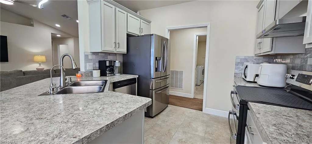 Kitchen with ventilation hood, stainless steel appliances, a sink, tasteful backsplash, and recessed lighting