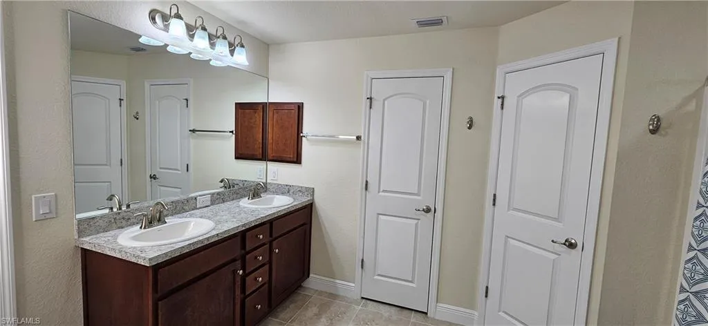 Full bathroom with double vanity, tile patterned flooring, a closet, and baseboards