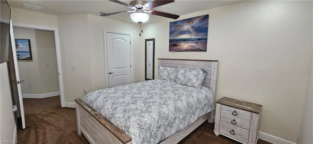 Bedroom with baseboards, dark carpet, and a ceiling fan
