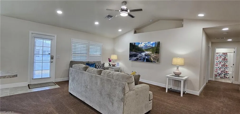 Living area with a ceiling fan, dark colored carpet, vaulted ceiling, recessed lighting, and baseboards