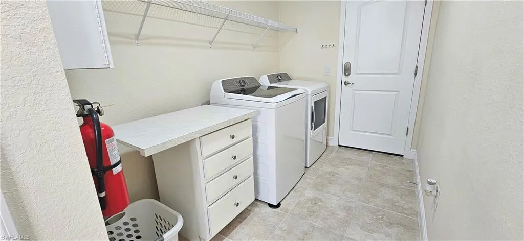 Laundry room featuring washer and dryer, a textured wall, and baseboards
