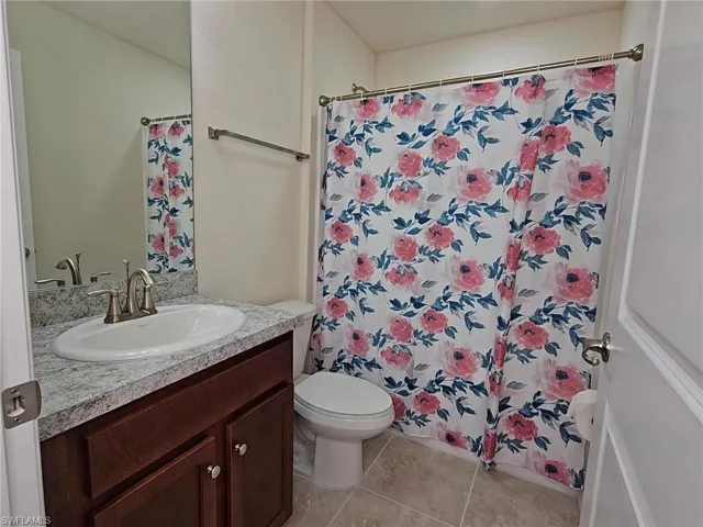 Bathroom with tile patterned floors, vanity, toilet, and a shower with curtain