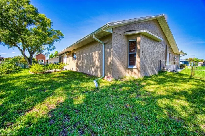 View of side of property with stucco siding and a gate