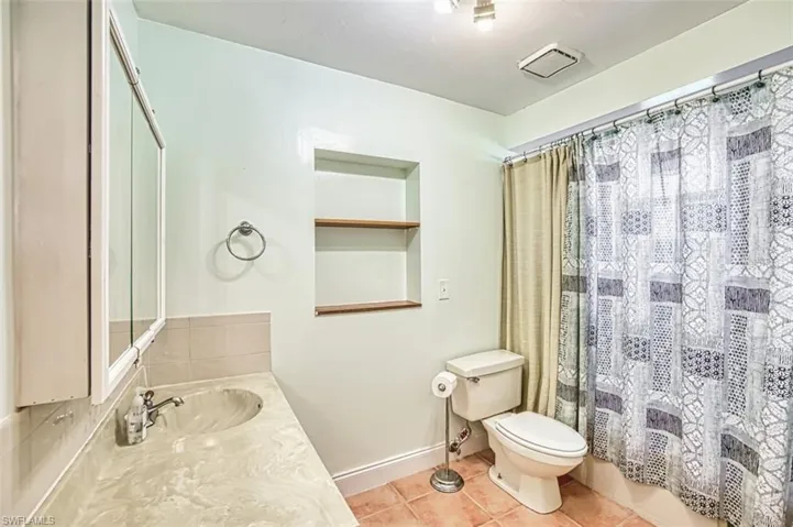 Full bathroom featuring tile patterned flooring, vanity, and curtained shower