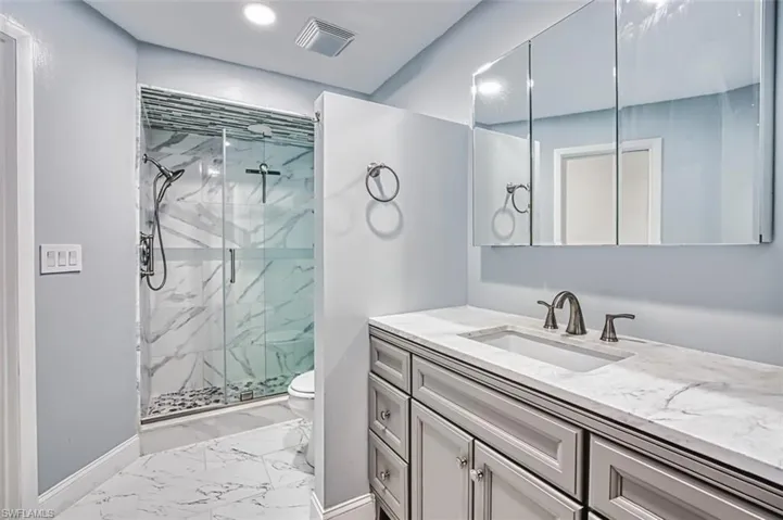 Bathroom with marble finish floors, a marble finish shower, vanity, and recessed lighting