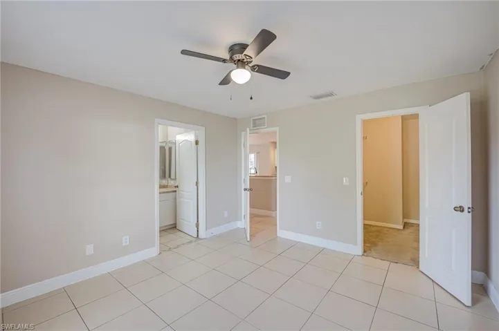 Spacious room featuring neutral paint, tile flooring, a ceiling fan with integrated lighting, and white baseboards