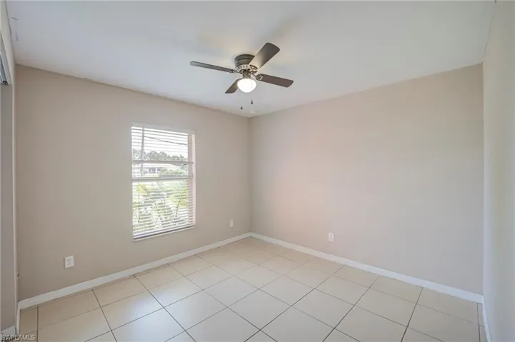 Neutral wall finish, tiled flooring, window with blinds, and a ceiling fan with integrated lighting