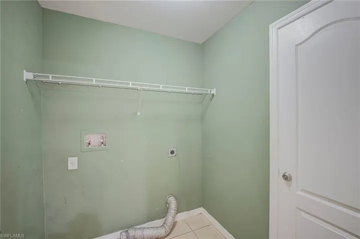 Dedicated utility space featuring tile flooring and light green walls