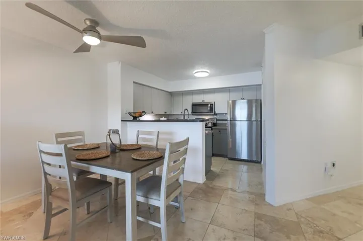 Tiled dining space with a textured ceiling and ceiling fan