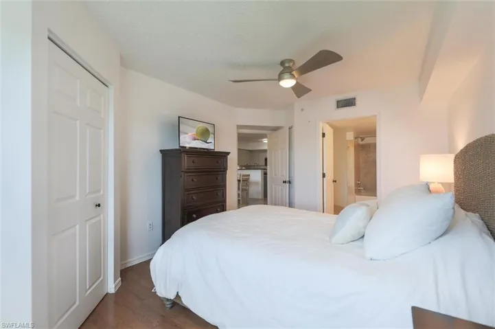 Bedroom with dark hardwood / wood-style floors, connected bathroom, a closet, and ceiling fan