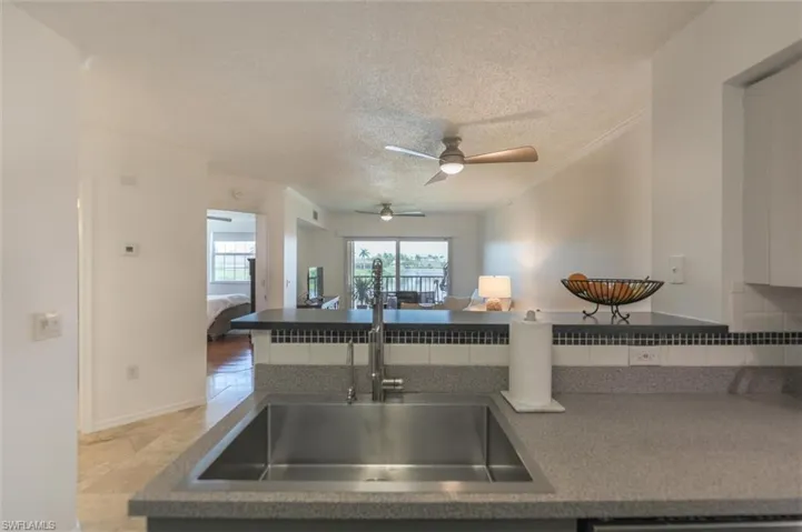 Kitchen featuring ceiling fan, crown molding, sink, a textured ceiling, and light tile patterned floors