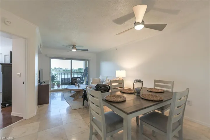 Dining room with light tile patterned floors, a textured ceiling, ceiling fan, and crown molding