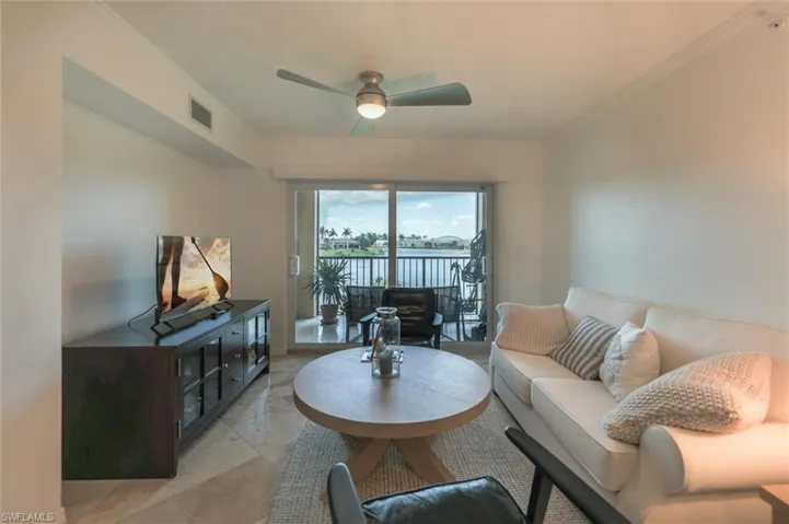 Living room featuring light tile patterned flooring, crown molding, and ceiling fan