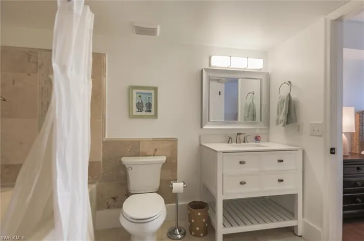 Full bathroom with vanity, shower / bath combo with shower curtain, tile walls, and toilet