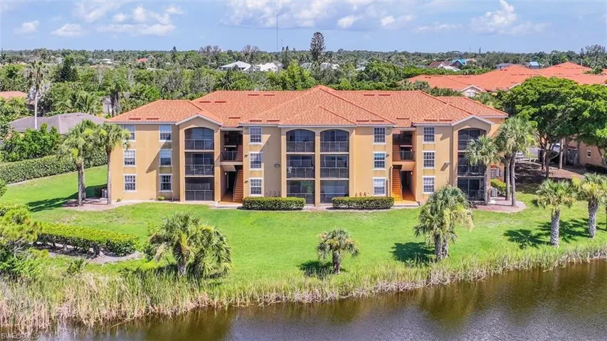 Rear view of property with a balcony, a water view, and a lawn