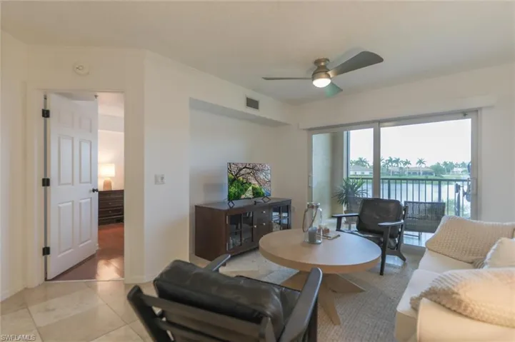 Living room with crown molding, light tile patterned floors, and ceiling fan