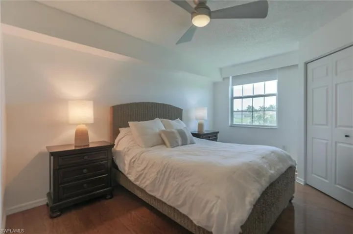 Bedroom with a closet, a textured ceiling, ceiling fan, and dark hardwood / wood-style floors