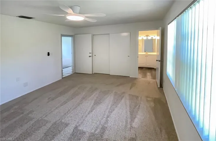 Unfurnished bedroom featuring carpet, connected bathroom, ceiling fan, and a closet