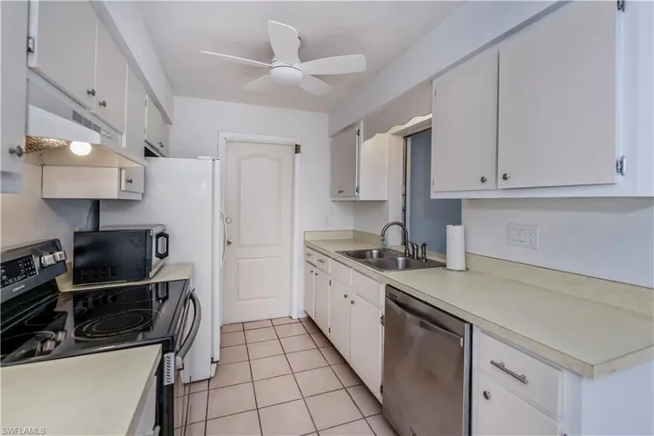 Kitchen with stainless steel stove, ceiling fan, sink, light tile floors, and white cabinets