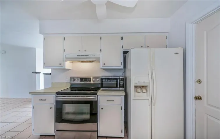 Kitchen with light tile flooring, white cabinetry, and appliances with stainless steel finishes