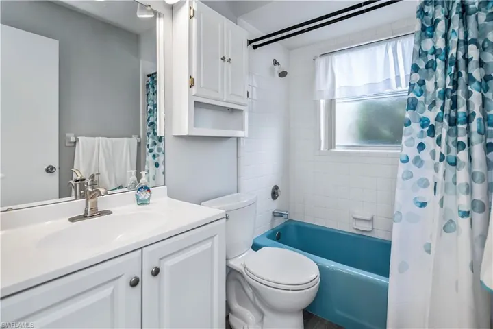Full bathroom with vanity, shower / bath combo, and toilet