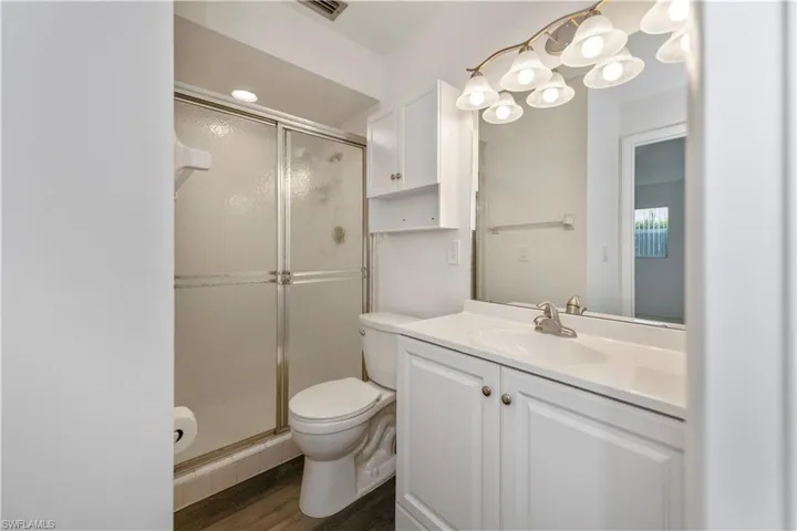 Master bathroom featuring vanity, wood-type flooring, an enclosed shower, and toilet