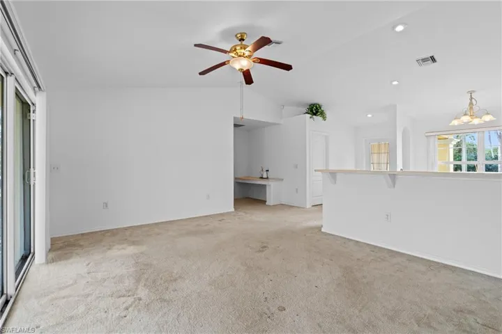 Unfurnished living room with lofted ceiling, a chandelier, recessed lighting, ceiling fan, and light carpet