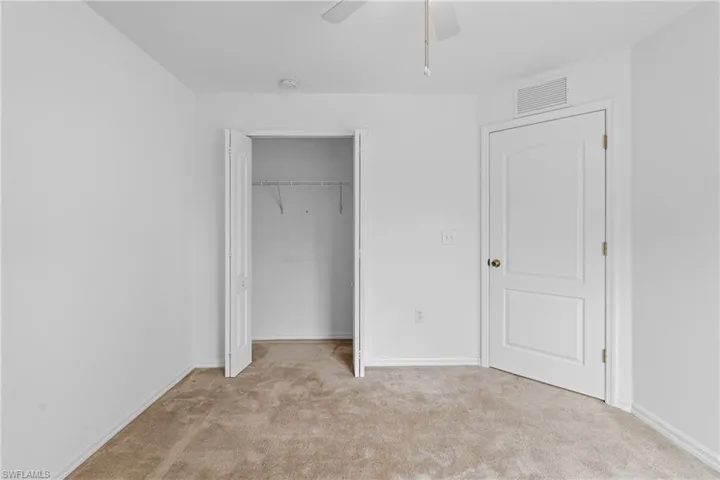 Unfurnished bedroom with light carpet, a closet, and a ceiling fan