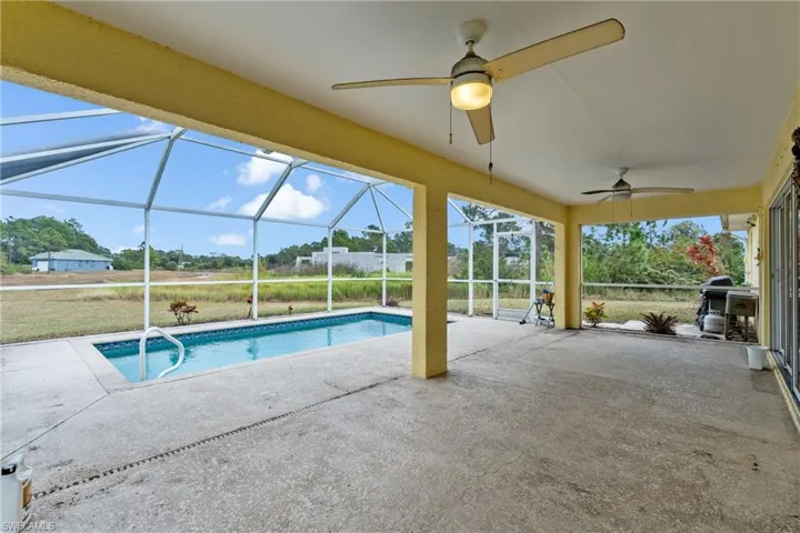 Outdoor pool featuring a patio, glass enclosure, a sunroom, and area for grilling