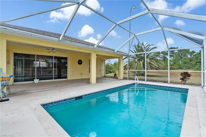 Outdoor pool featuring a sunroom, glass enclosure, and a patio
