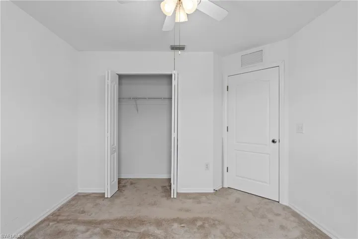Unfurnished bedroom with light carpet, a closet, and a ceiling fan