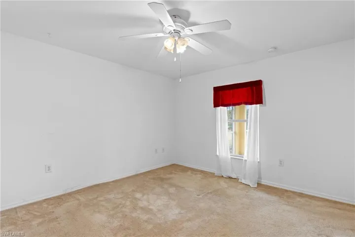 Spare room featuring a ceiling fan and light carpet